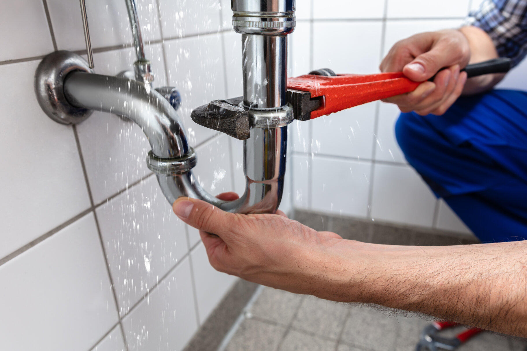 Person using a wrench working on plumbing